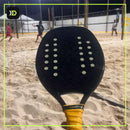 Raquete Hoowan Blackshark fincada na areia em quadra de beach tennis